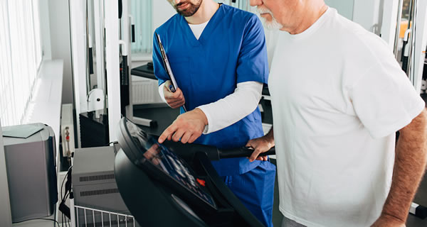 Krankengymanstik an medizinischen Trainingsgeräten unter Anleitung eines Physiotherapeuten